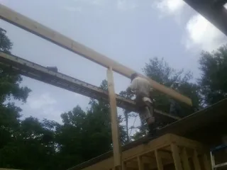 Carpenter setting a ridge beam over a new addition frame — Ice Dam Removal by Roofing Brothers in Gray